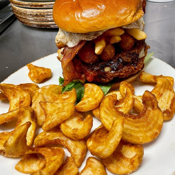 A Texas Forever Bar and Grill burger with bacon, fried egg, fries, and curly fries.