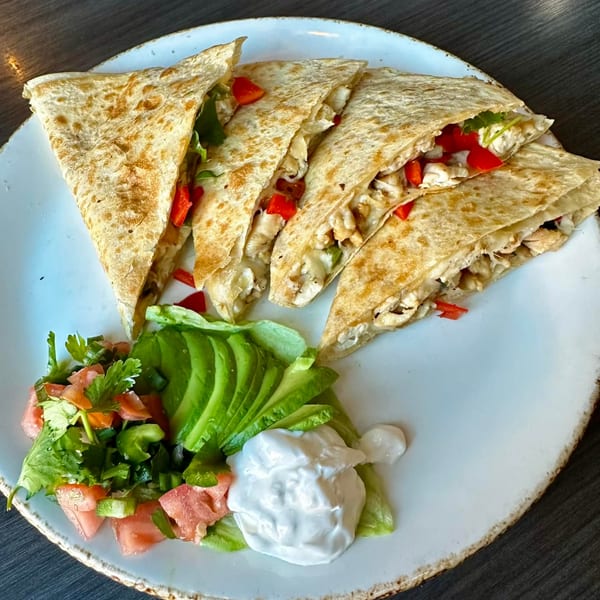 Chicken quesadillas with red peppers, served with avocado slices, pico de gallo, and sour cream.